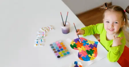 criança-brincando-com-tinta-e-pintando-um-coração-com-várias-cores-que-representam-o-autismo